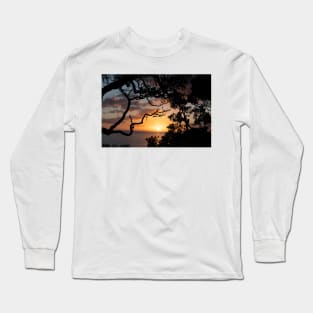 Sunrise over coast framed by silhouette foliage of pohutukawa tree on edge of slope. Long Sleeve T-Shirt